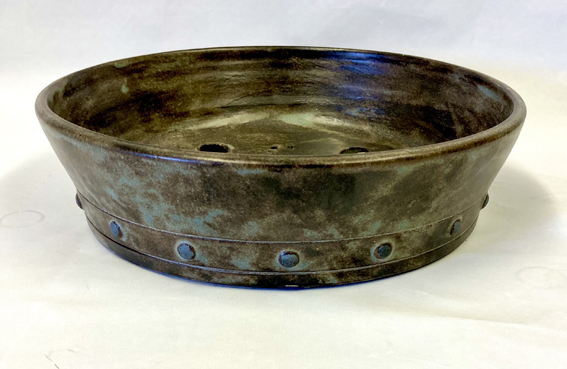 hand-thrown stoneware clay with a green glaze and applied bullets decorated with iron oxide