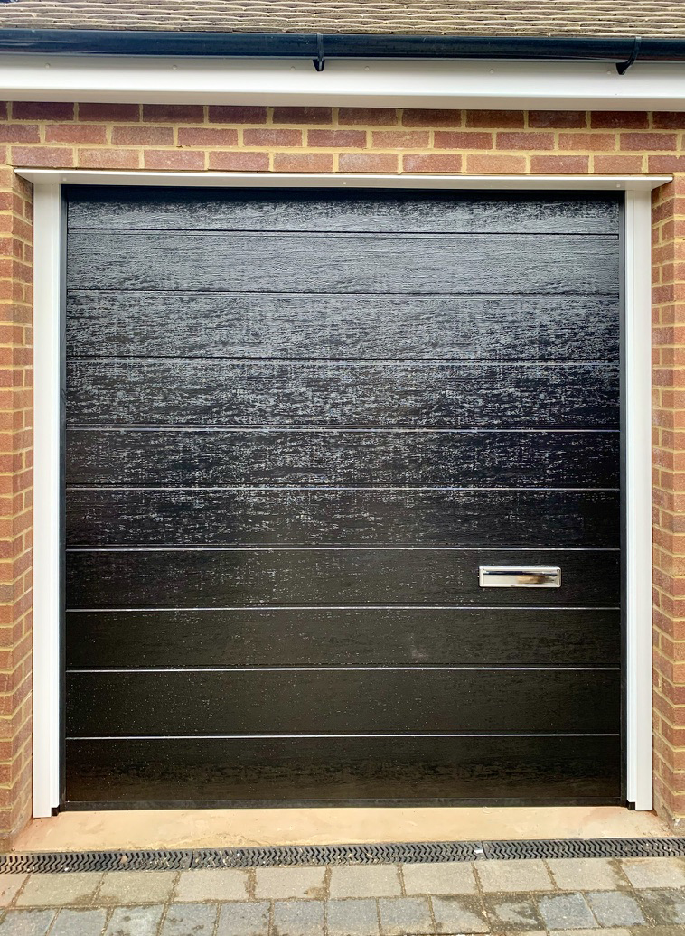 Single Insulated Woodgrain (Black) M-Ribbed Sectional Garage Door with Letterbox.