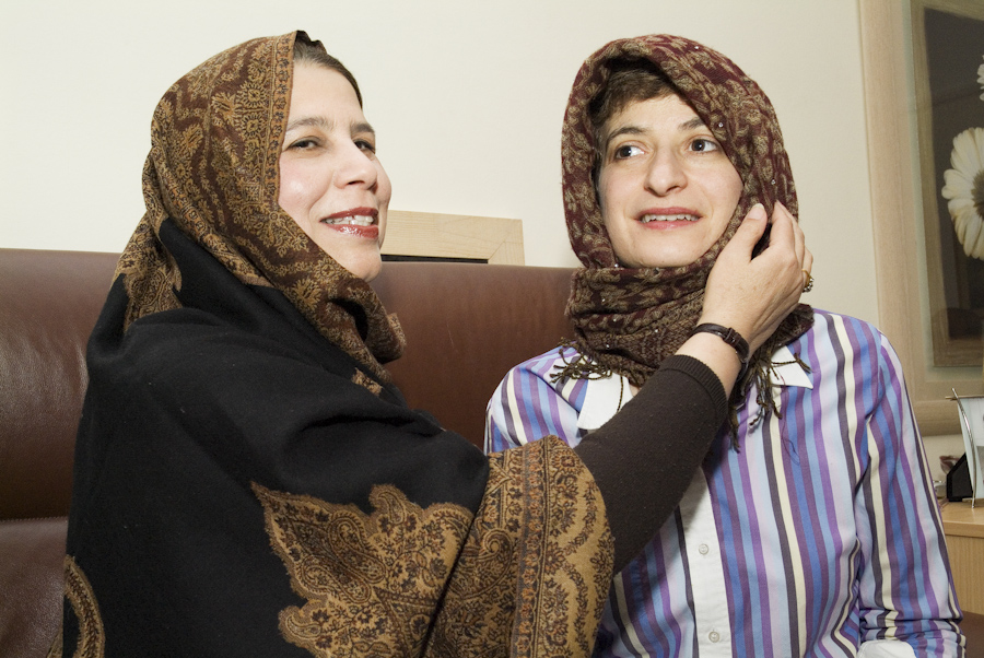 A Muslim woman puts a traditional head scarf on a Jewish woman