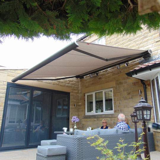 A family enjoying relaxing under their Alcas Awning